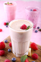 Milkshakes at cutting board with berries on light background, close-up