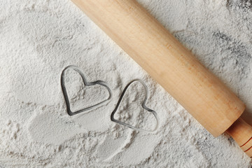 Hearts of flour and rolling pin on gray background