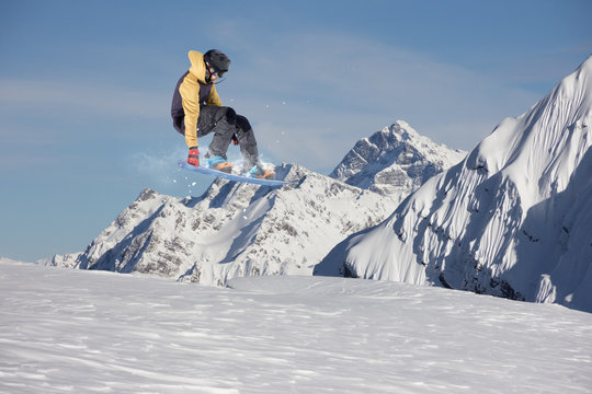Flying snowboarder on mountains. Extreme sport.