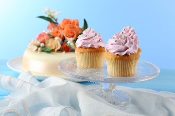 Tasty cupcakes on stand and cake, on table, on color background