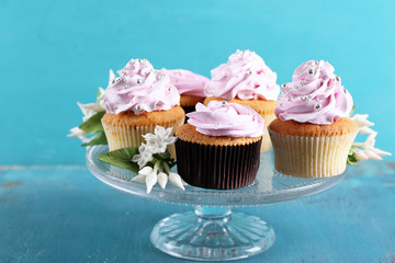 Tasty cupcakes on stand, on color wooden background