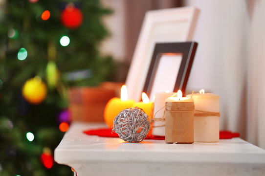 Candles and frames on fireplace in decorated Christmas room, close up