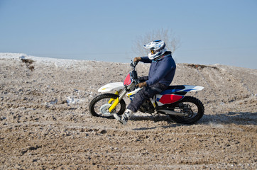 MX rider on a snowy hill with a slope turns motorcycle 