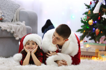 Obraz premium Happy father and daughter on the floor in the decorated Christmas room
