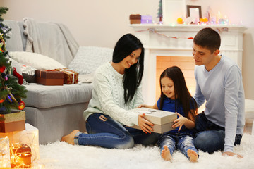 Happy family on the floor with gifts in the decorated Christmas room