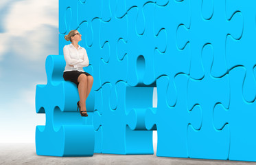 Business woman building a blue puzzle on a sky background
