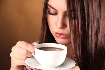 Woman holds cup of coffee and saucer in hands, close up