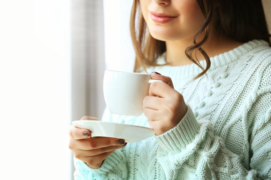 Woman holds cup of coffee in hands, close up