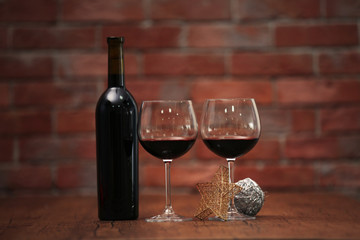 Red wine and Christmas ornaments on wooden table on wall brick background