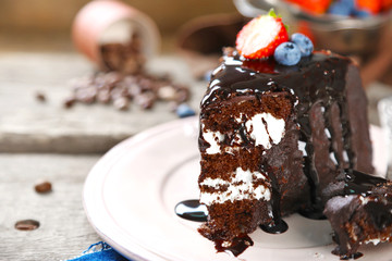 Chocolate cake with cream and fresh berries on plate, on wooden background
