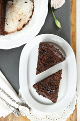 Sliced chocolate cake on plate, on wooden table  background