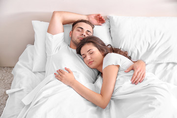 Happy couple snoozing on bed