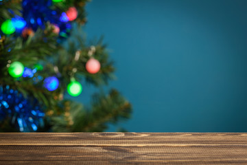 Wooden table with Christmas tree in the background. Focus on the table