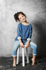 Portrait of little fashion kid girl on gray wall background