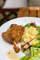 Dish with a roasted duck leg and green salad
