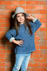 Portrait of little fashion kid girl on bricks wall background