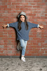 Portrait of little fashion kid girl on bricks wall background