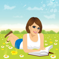 Obraz na płótnie Canvas woman lying down on grass reading book