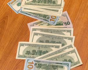 american dollar bills carelessly scattered on the wooden table