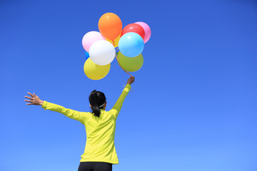 cheering young woman with colorful balloons