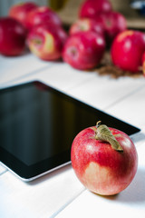 Tablet with apples on a white wooden background
