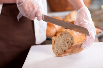 Skillful female baker is serving her customers