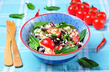 Couscous salad and brown beans, with olive oil, with organic cherry tomatoes, onion, parsley and spinach