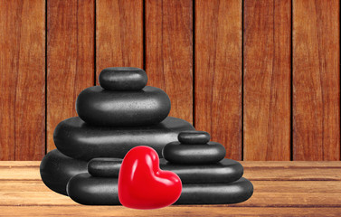 Spa stones and red heart on wooden table over wooden background