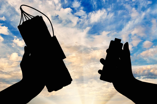 Silhouette of hands with bomb and detonator against cloudy sky