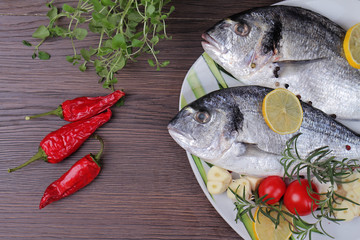 Fresh raw sea bream fish  decorated with lemon and herbs on blue wooden background. Healthy food concept