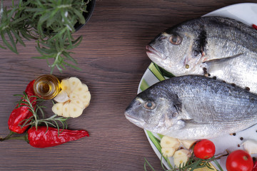 Fresh raw sea bream fish  decorated with lemon and herbs on blue wooden background. Healthy food concept