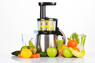 Slow juicer with fruit, vegetables and a glass of fresh juice on white table with white background, for a healthy lifestyle