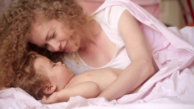 Beautiful young mother tenderly kissing the sleeping baby, mother and son, children's sleep