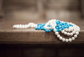 Fototapeta na wymiar pearls and turquoise beads hang from the edge of the table