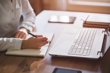 Woman freelancer female hands with pen writing on notebook at home or office