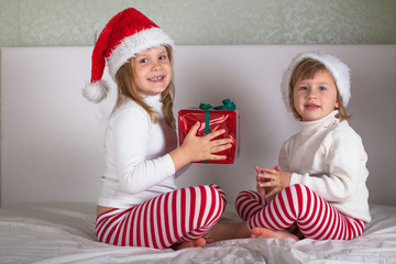 funny kids in their pajamas and Christmas caps on the bed