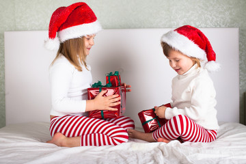 funny kids in their pajamas and Christmas caps on the bed