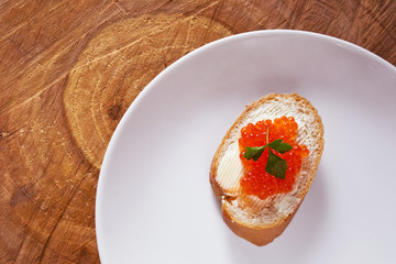 Sandwich with red caviar on white plate 