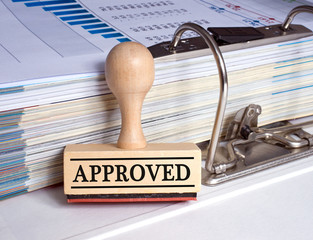Approved - rubber stamp with text and binder with documents in the office