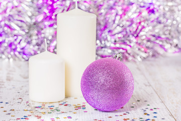 Obraz na płótnie Canvas Christmas ball and two white candles, close-up
