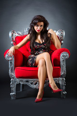Fototapeta na wymiar Young woman in a red chair. Retro style.