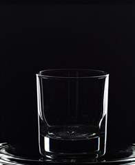 An empty cocktail glass rimmed with light against a black background.