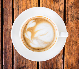  A cup of coffee with leaf pattern in a white cup on wooden background