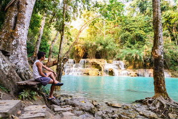 Man waiting for someone at rainforest waterfall, Tat Kuang Si Waterfall at Luang Prabang, Loas.