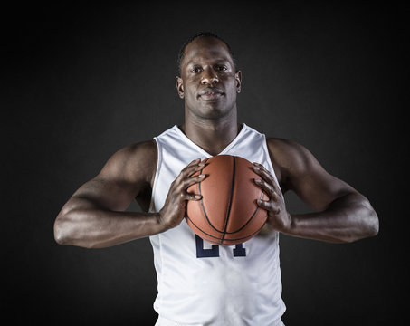 African American Basketball Player portrait holding a ball. Black background
