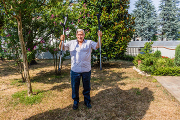 old man triumphantly holding crutches in garden