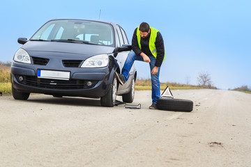 Fototapeta na wymiar Man fixing his flat tire on the car