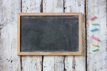 top image of chalkboard and colorful chalks over wooden table
