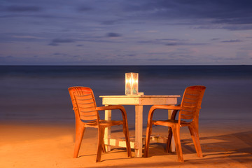 Wild beautiful beaches of Sri Lanka in the night. Table with chairs and candle.