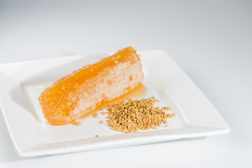Honey comb and bee pollen falls flow in the white plate (shallow